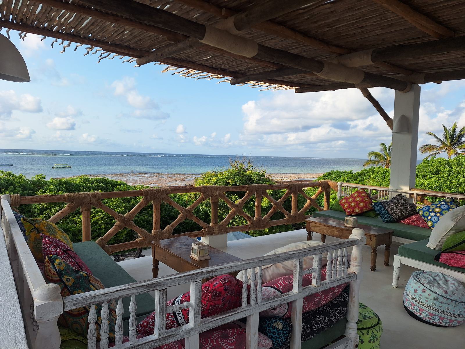 Covered view deck with cushioned sofas looking over the gardens to the Indian Ocean at Turtle Bay