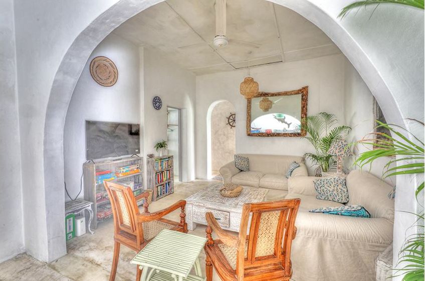 Living room seen through an arch, with sofas, TV and bookshelves